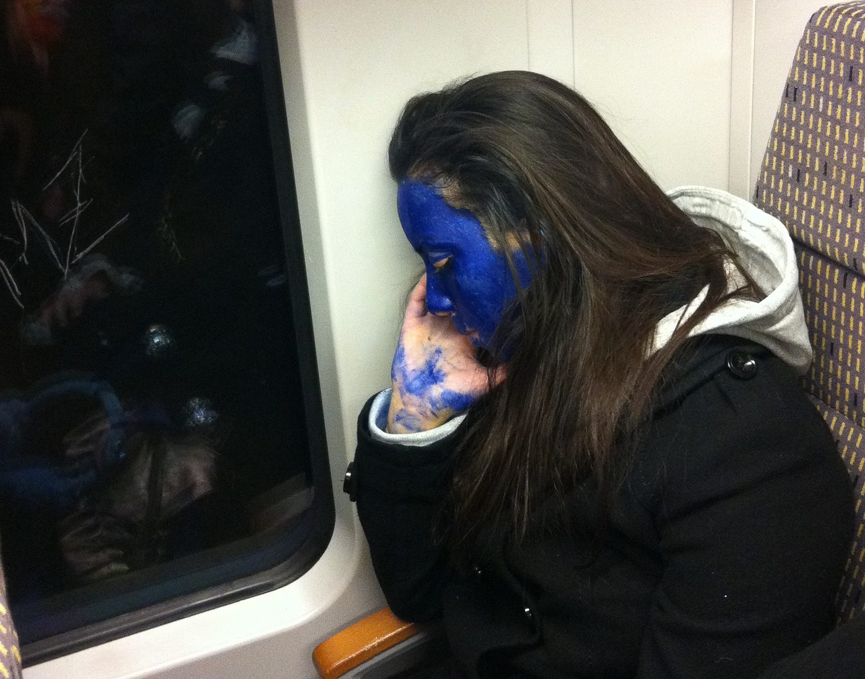 Eingeschlafene geschminkte Frau in einem Zug während des Kölner Karnevals