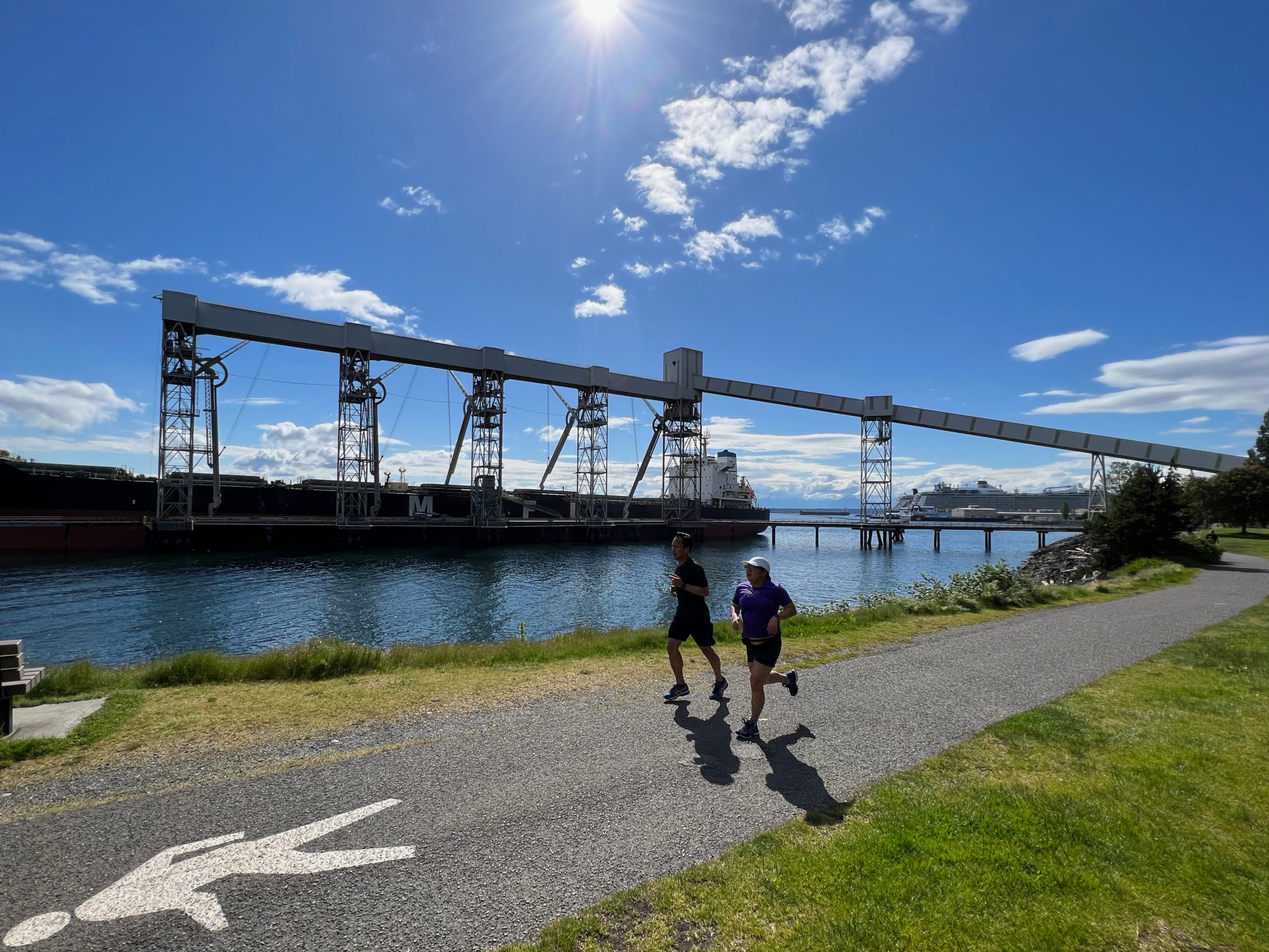 Jogger auf einem Weg am Port of Seattle mit Schiff im Hintergrund
