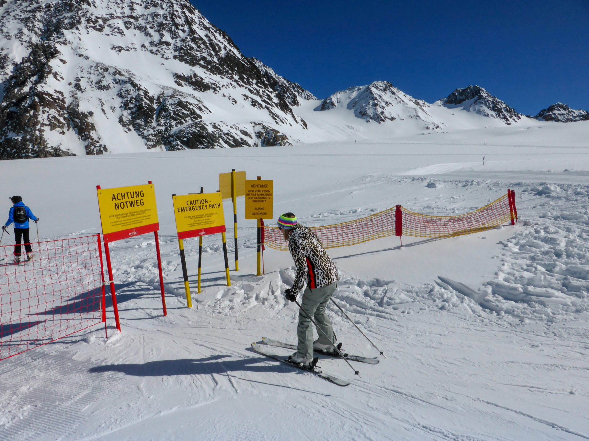 Skiläuferin duckt sich unter einem Schild hindurch im Pitztal