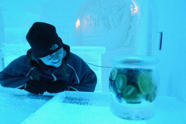 Frau begutachtet gefrorenes Obst im norwegischen Eishotel