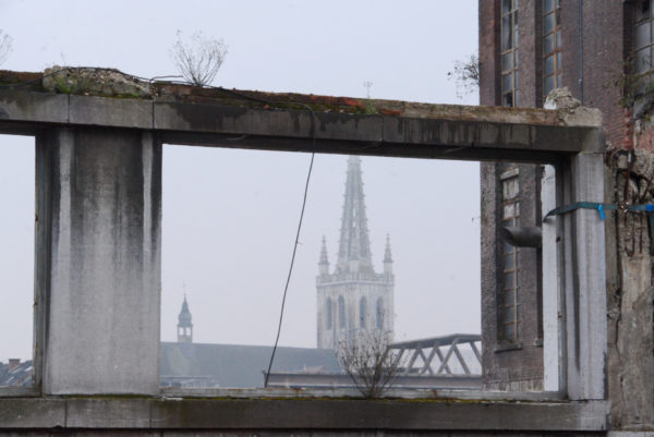 Der Kirchturm von Leuven gesehen durch einen verwitterten Betonrahmen