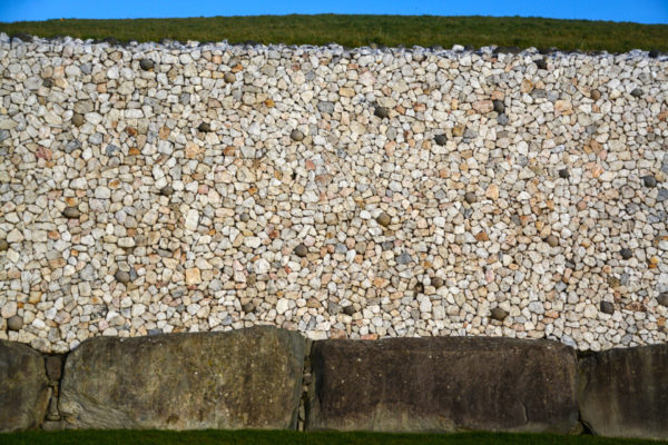 Natursteinmauer eines Hügelgrabs im irischen Newgrange unter einer Grasfläche