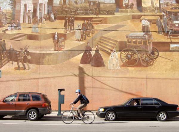 Radfahrer mit Helm vor einem Wandgemälde auf einer Straße in Toronto