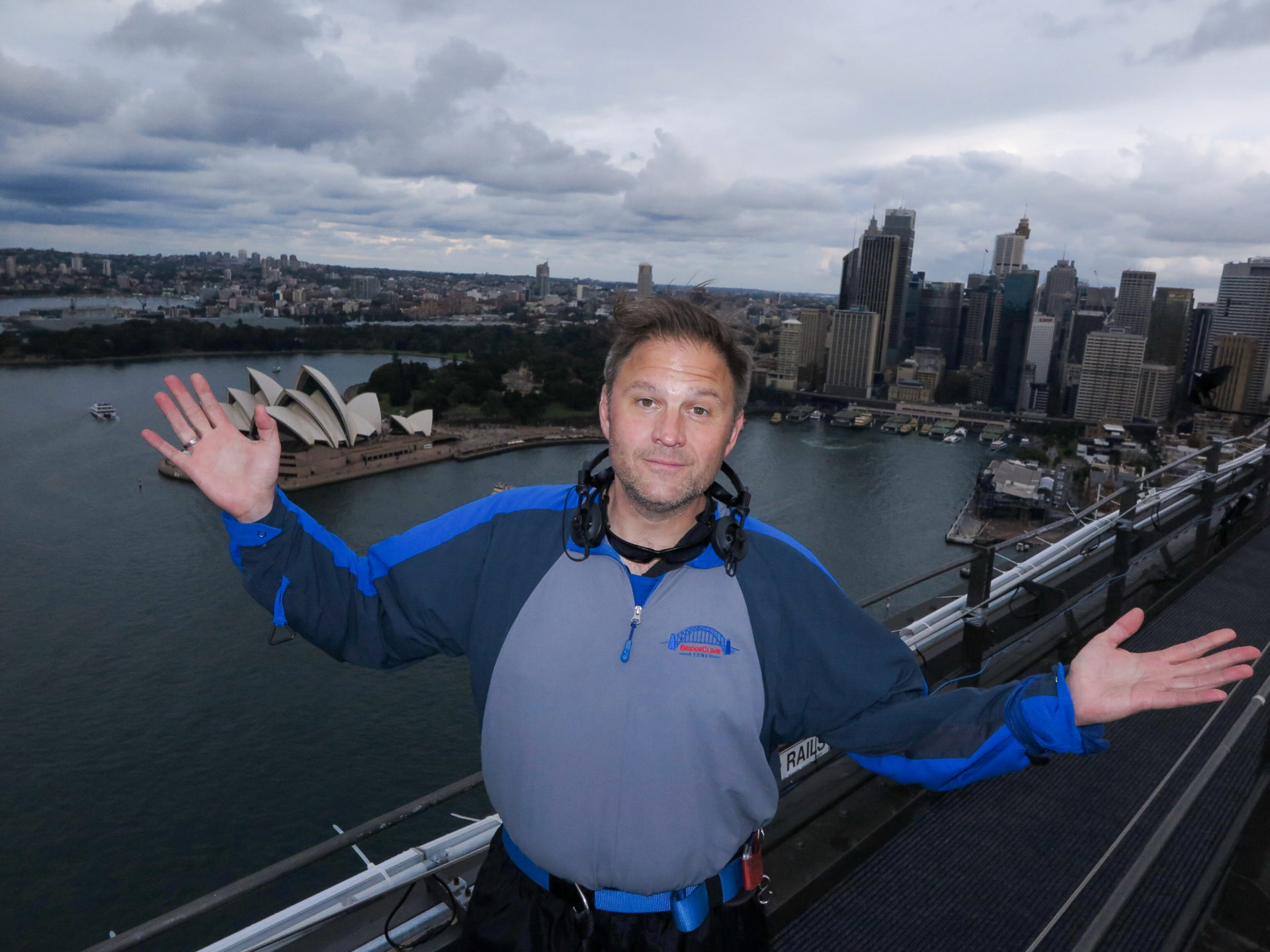 Autor Ralf Johnen vor der Skyline von Sydney mit Opernhaus an einem wolkigen Tag