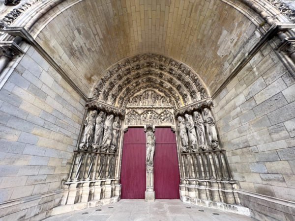 Eingangsportal zur kathedrale von Laon mit Statuen und roter Holztüre