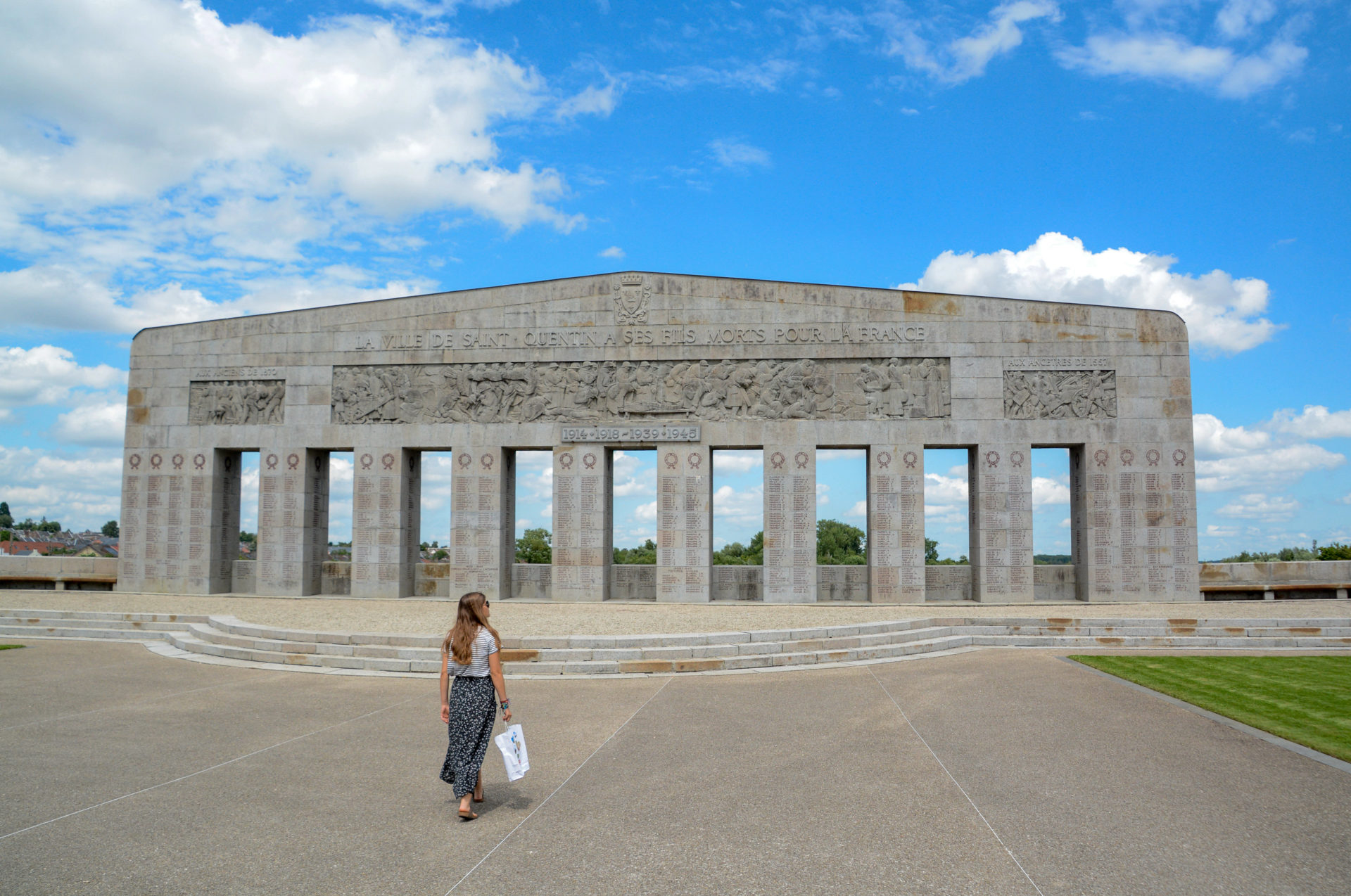 Monument in Gedanken an die Opfer des Ersten und Zweiten Weltkriegs in der nordfranzösischen Stadt Saint-Quentin mit Frau davor
