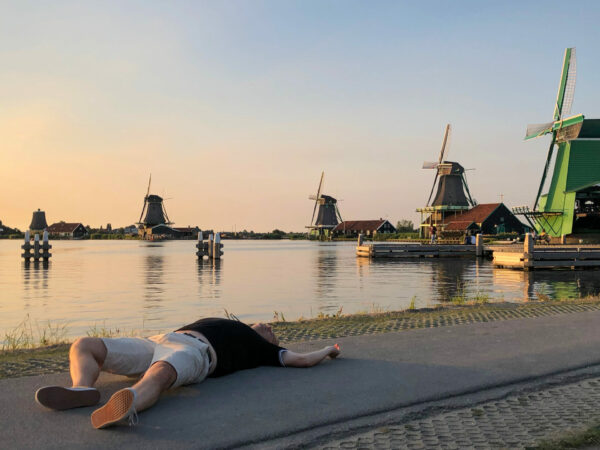 Mann liegt auf der Straße vor den Windmühlen bei Zaandam