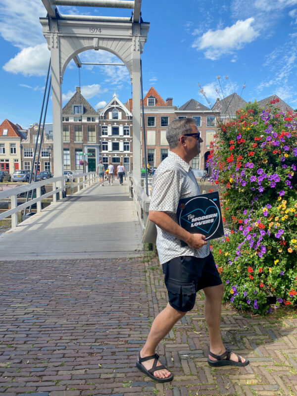 Autor Ralf Johnen mit einer Schallplatte von den Modern Lovers vor einer Holzbrücke in Zwolle