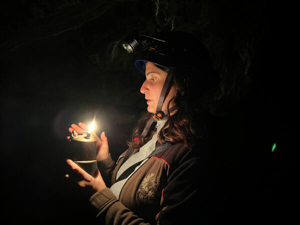 Frau mit Licht und Helm in einem Stollen der Mineria Sant Aloisio