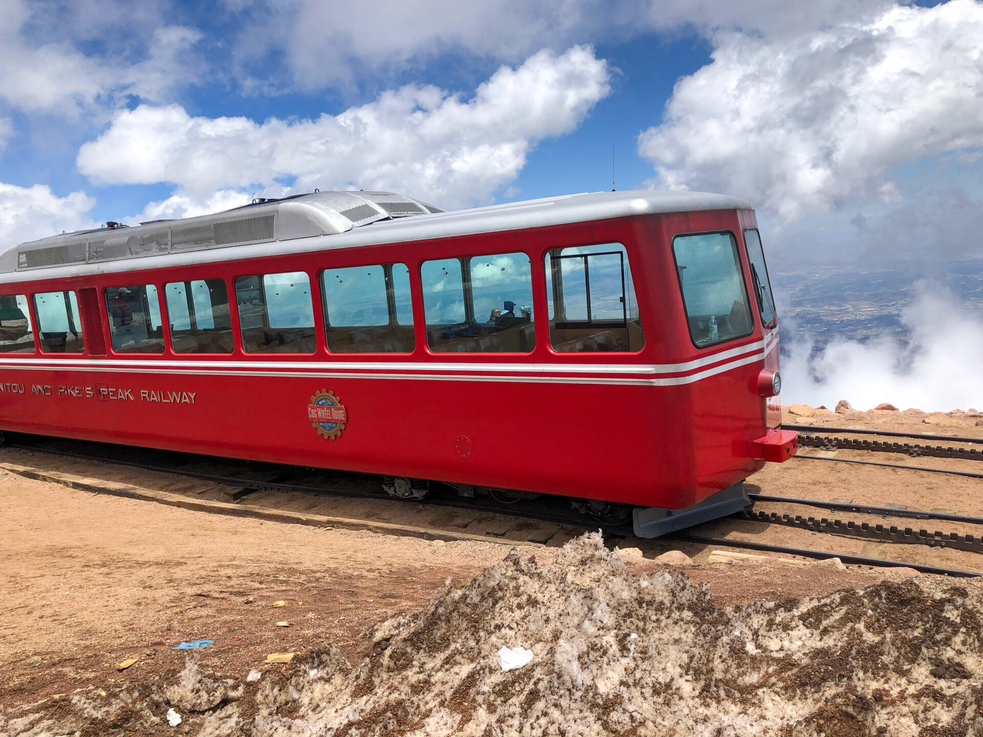 Die knallrote Cog Railway beim Aufstieg auf den Pikes Peak in Colorado mit Wolken im Hintergrund