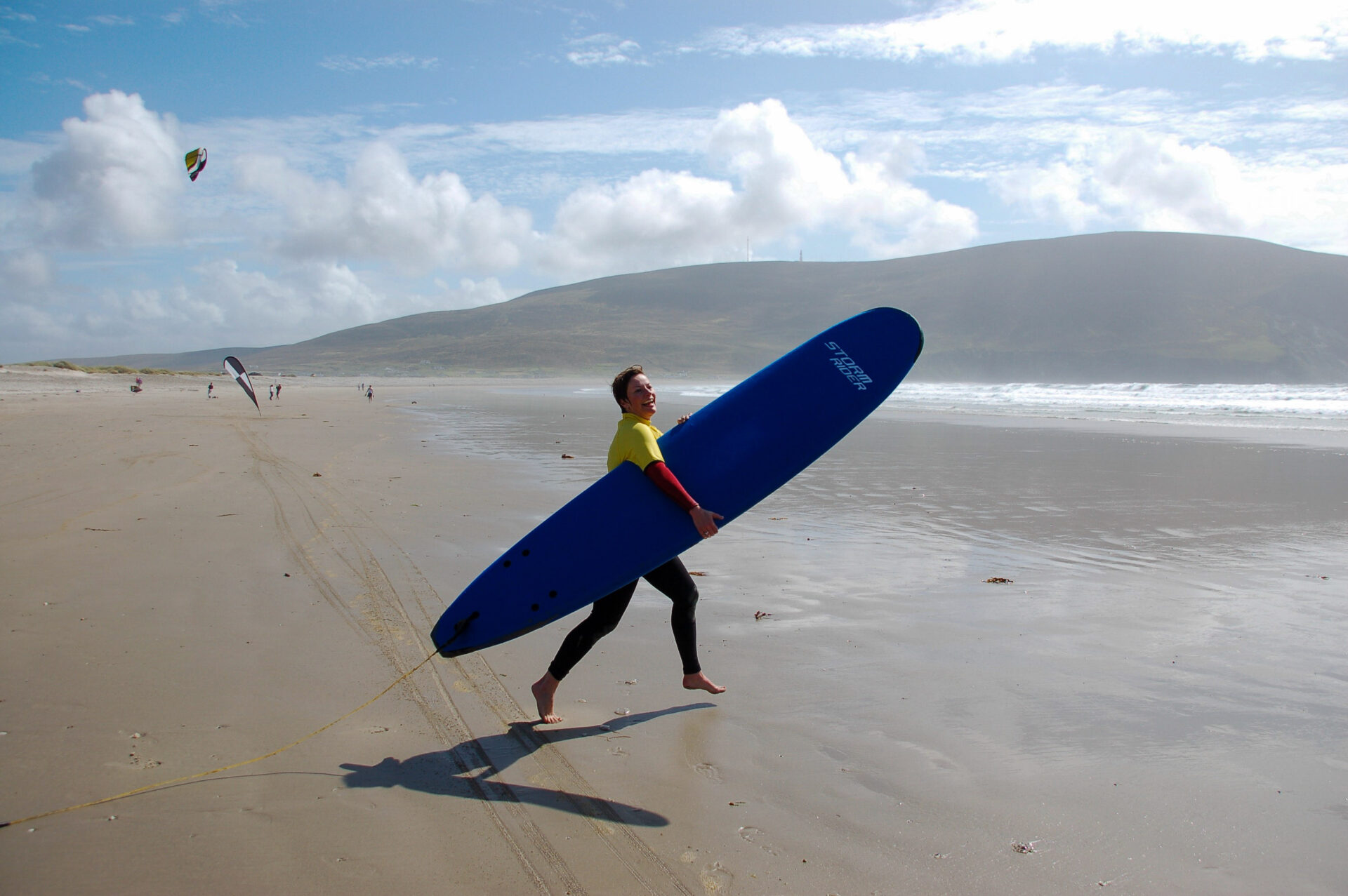 Ausgelassene Frau sprintet mit Surfbrett ins Wasser auf Achill Island