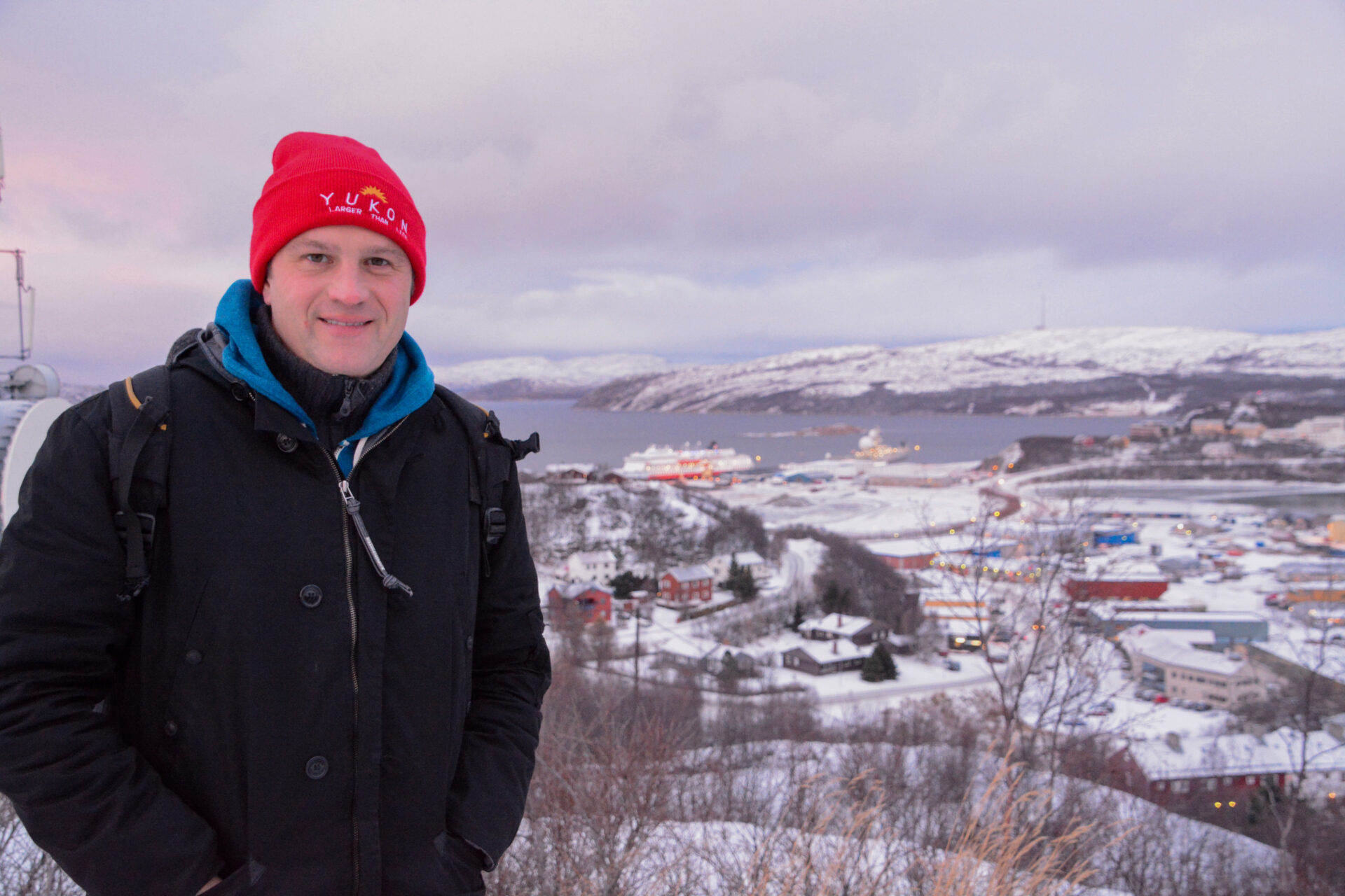 Autor Ralf Johnen auf einer Anhöhe über dem Hafen von Kirkenes mit der MS Finnmarken von Hurtigruten im Hintergrund