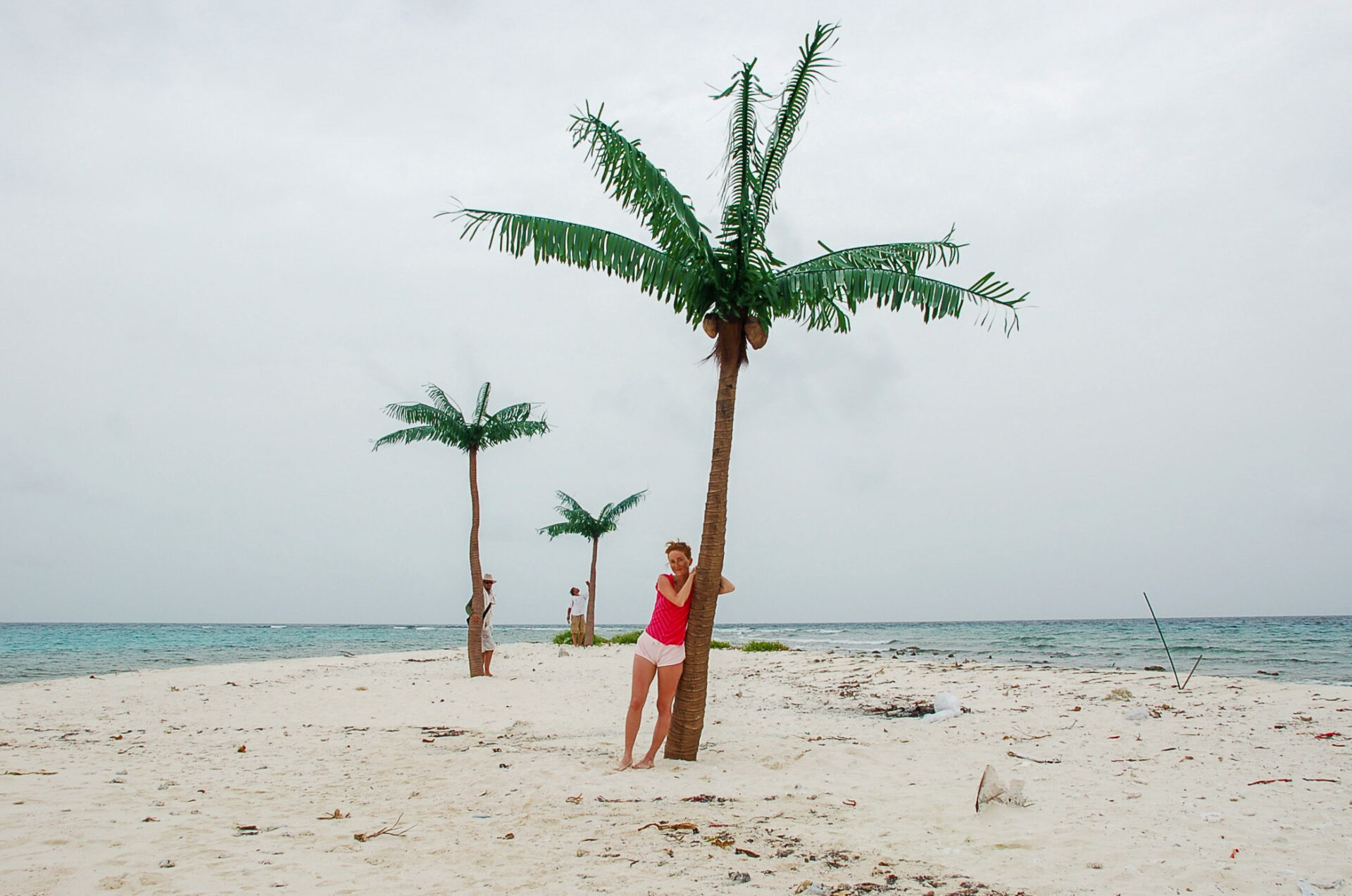 Frau lehnt an Palme auf der Insel Anegada auf den British Virgin Islands