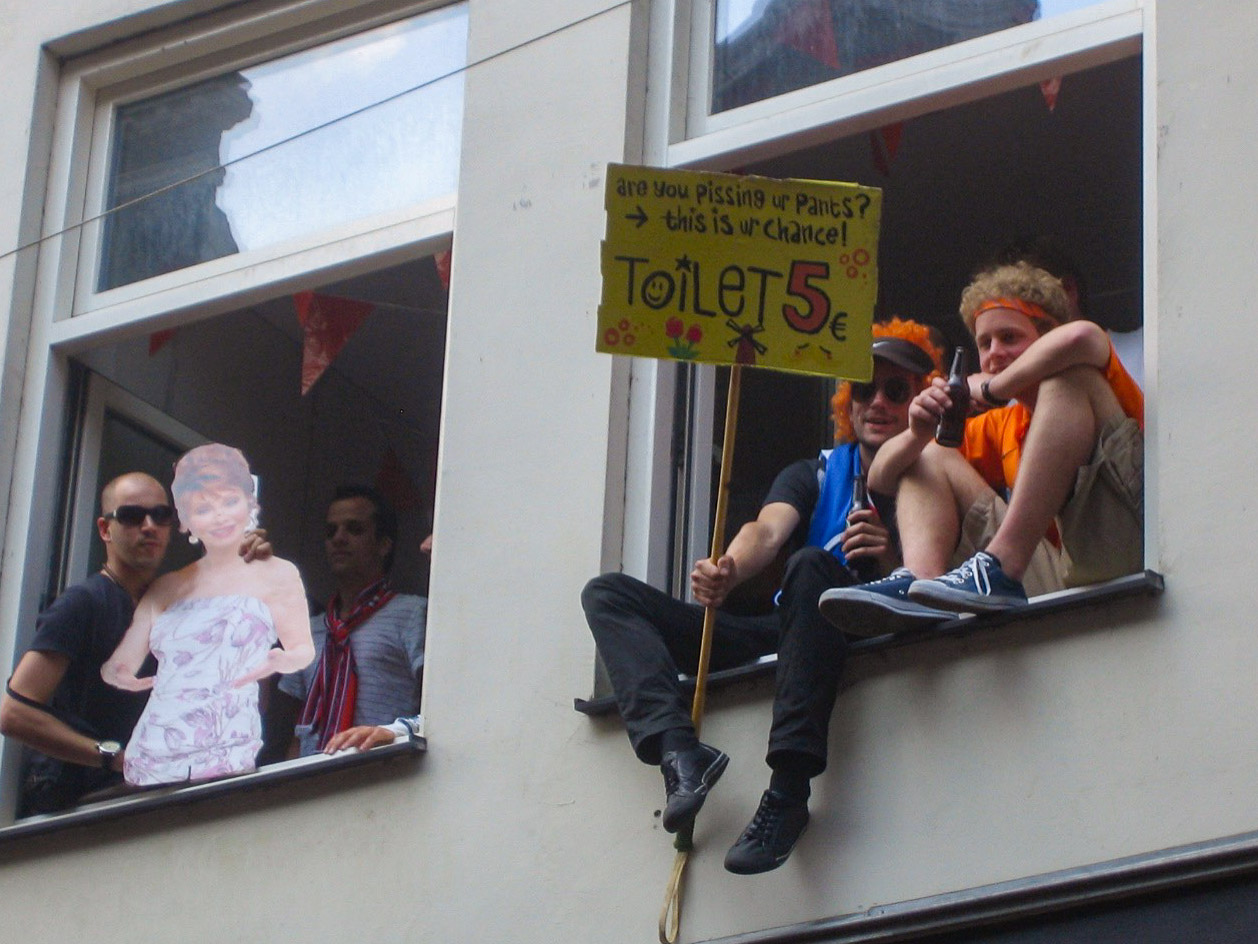 Schild mit Preis für Toilettenbenutzung beim Königstag in Amsterdam in einem Fenster