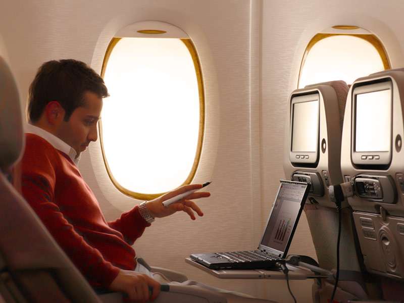 Economy-Passagier mit Laptop an Bord eines Airbus 380 von Emirates