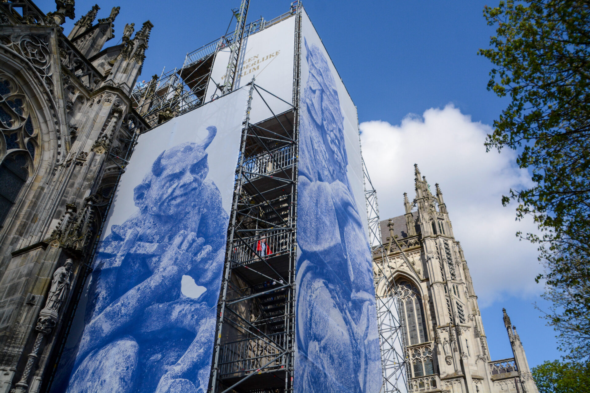 Plakate und Gerüst an der Kathedrale von Den Bosch, auf deren Dach Fantasiefiguren aus der Fabelwelt von Hieronymus Bosch stehen