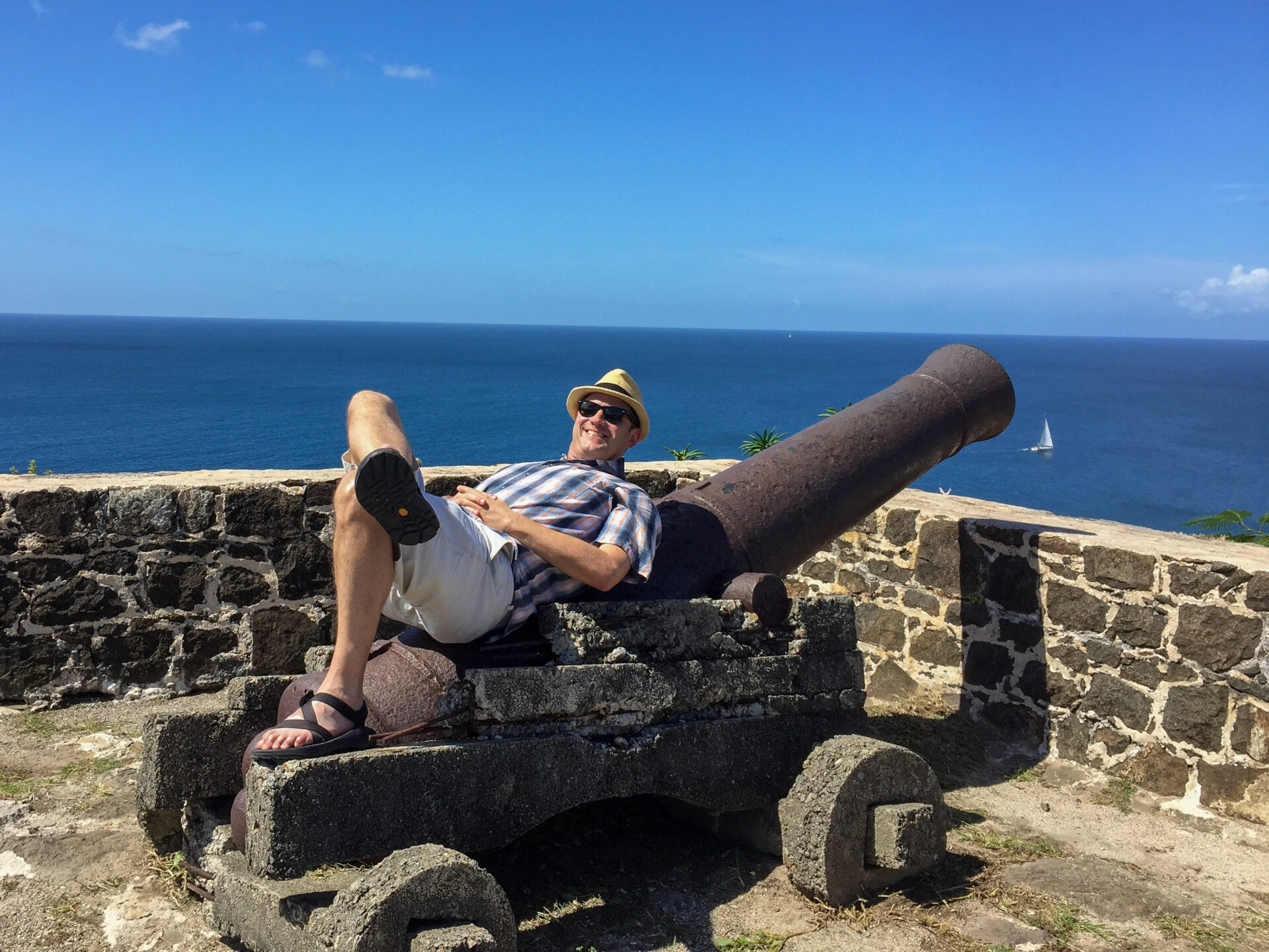 Mann liegt auf einer Kanone auf der Insel St. Lucia mit Karibischem Meer im Hintergrund