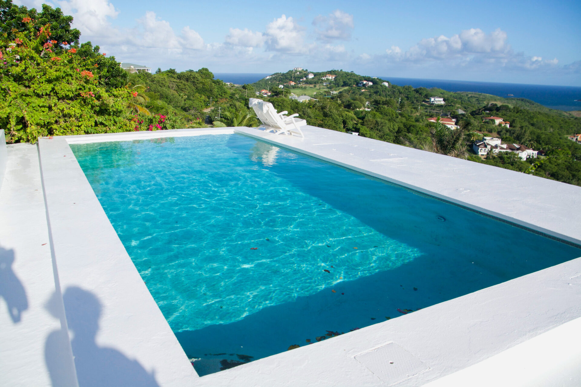 Pool mit weißer Umrandung auf einem Berg hoch über St. Lucia mit Blick aufs Meer