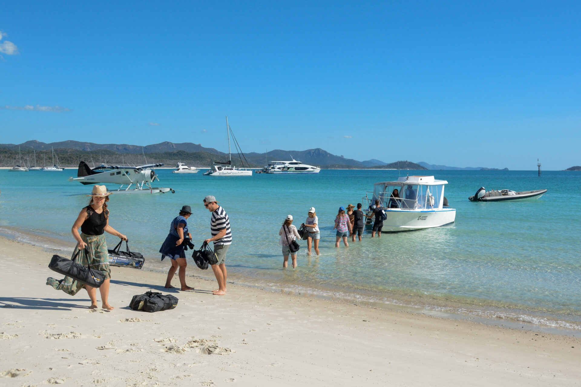 Eine Gruppe von Touristen kommt per Boot am Whitehaven Beach an und schleppt Ausrüstung und Proviant an Land