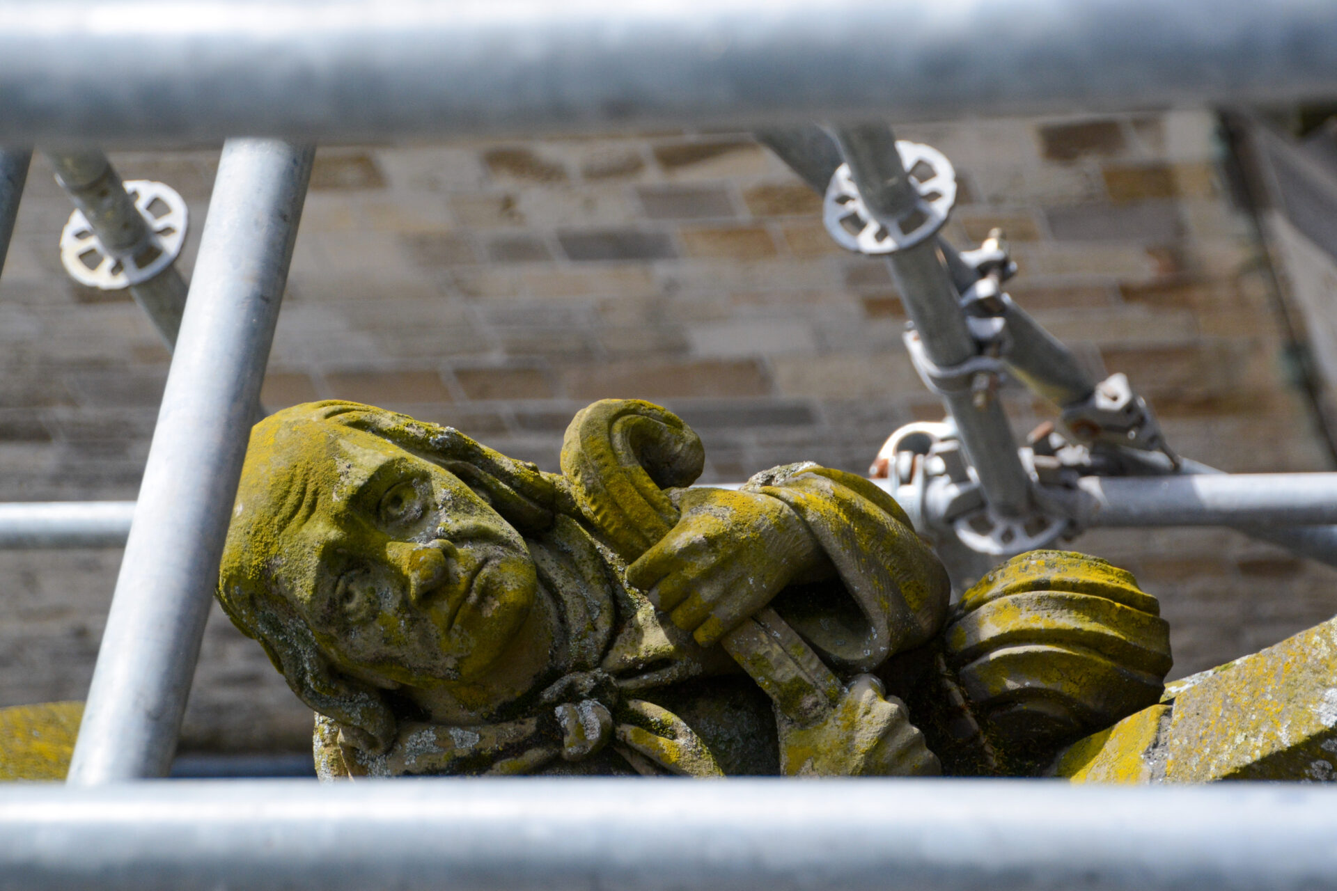 Traurig blickende Figur inmitten einer Gerüstöffnung auf dem Dach der Kathedrale von Den Bosch