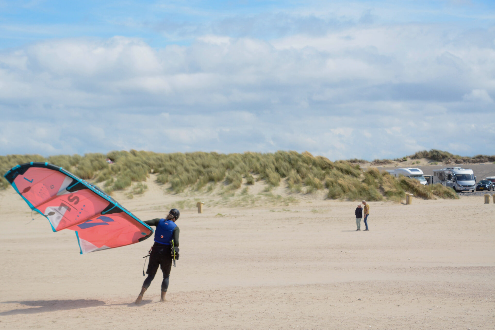 Kitesurfer trägt sein Segel zum Parkplatz am Brouwersdam in den Niederlanden