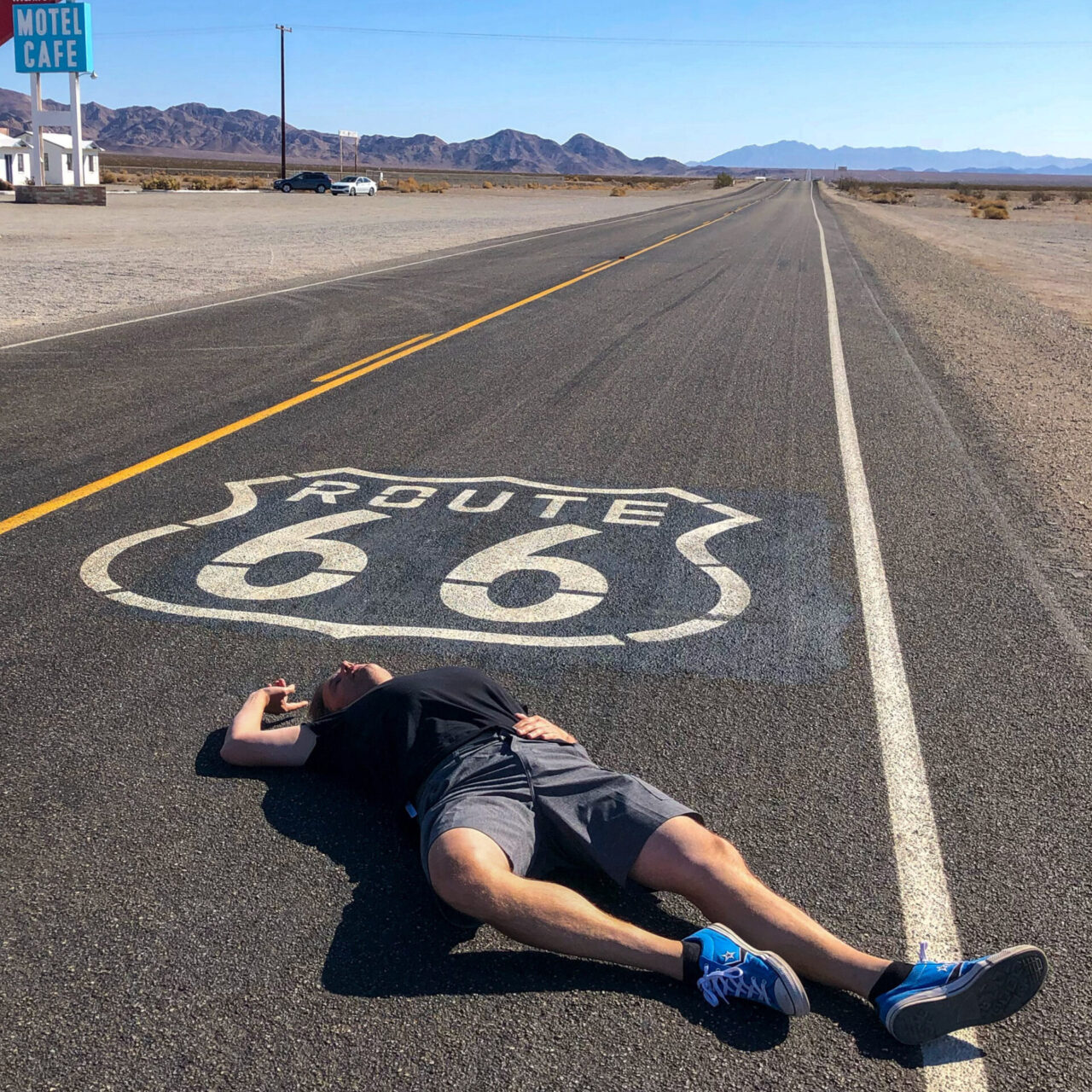 Mann liegt vor Logo der Route 66 auf der Straße in Kalifornien