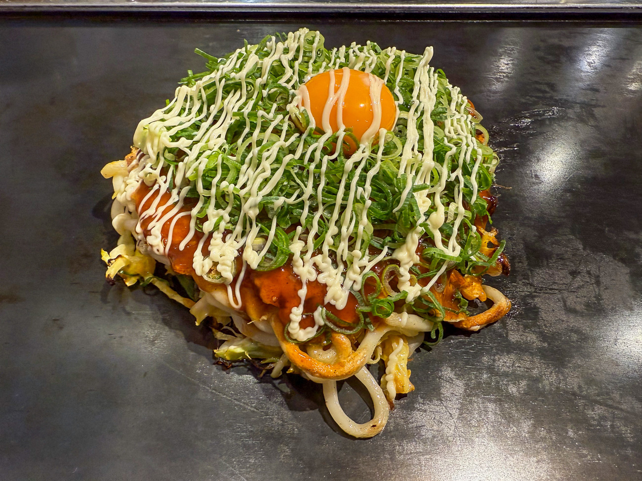 Street Food Okonomiyaki auf einer Grillplatte in Osaka