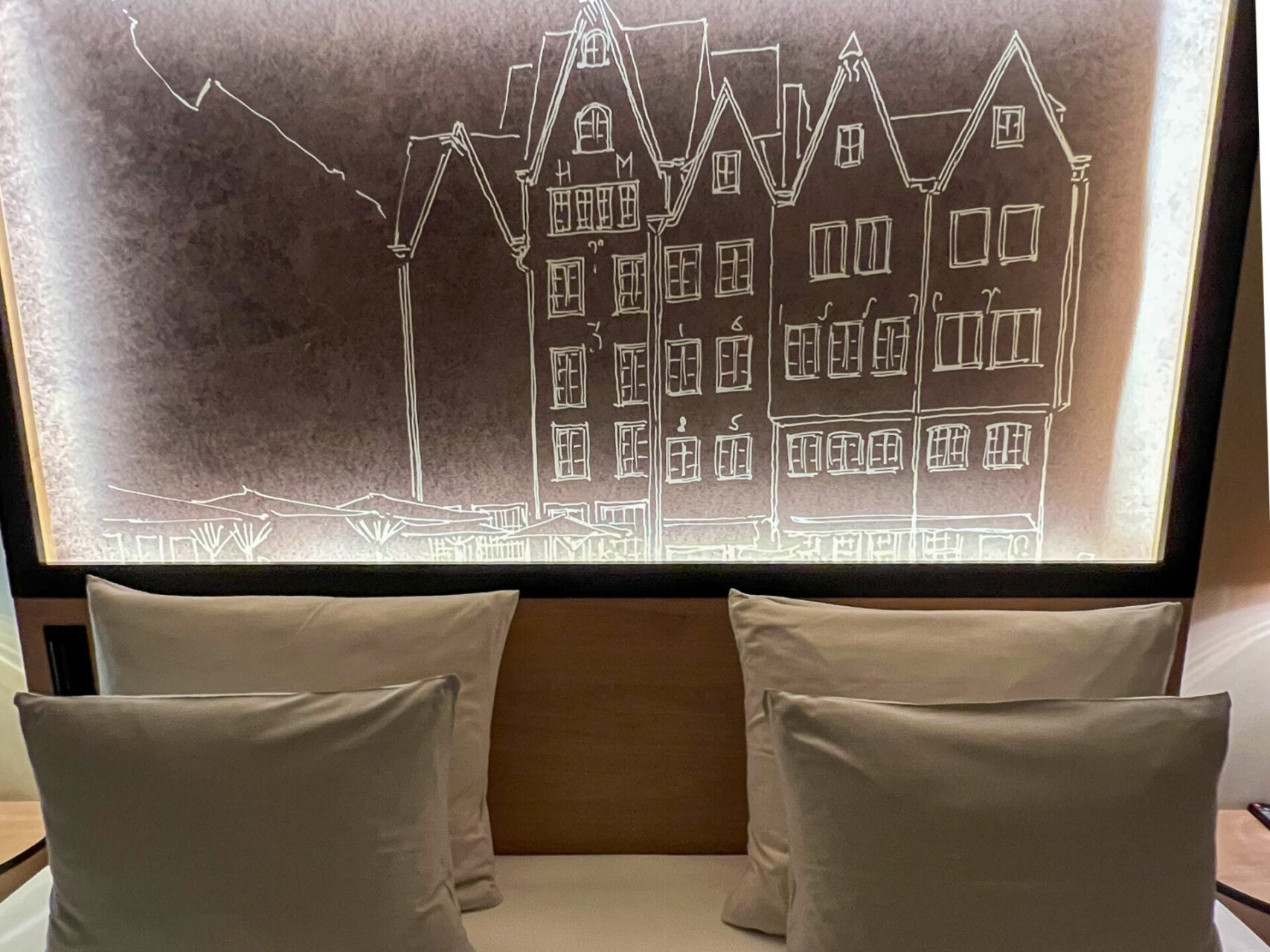 Bett mit Kopfkissen und Bild der Kölner Altstadt in der Juniorsuite des alten Wasserturms in Köln