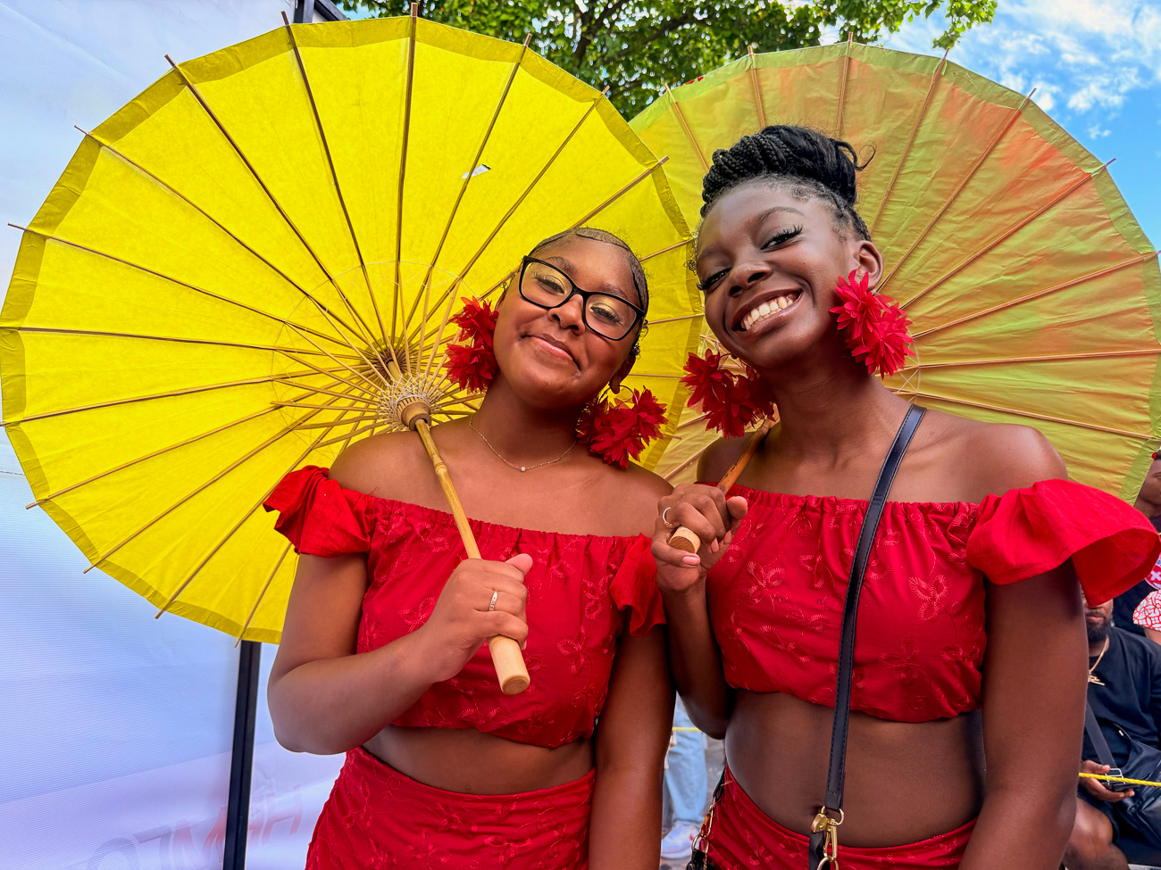 Mädchen in roten Kleidern mit gelben Sonnenschirmen beim Karneval auf Sint Maarten