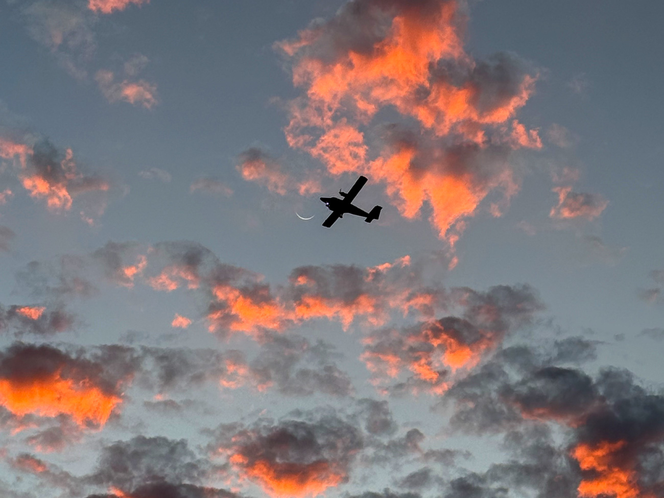 Propellermaschine mit Mondsichel über dem Abendhimmel auf Sint Maarten