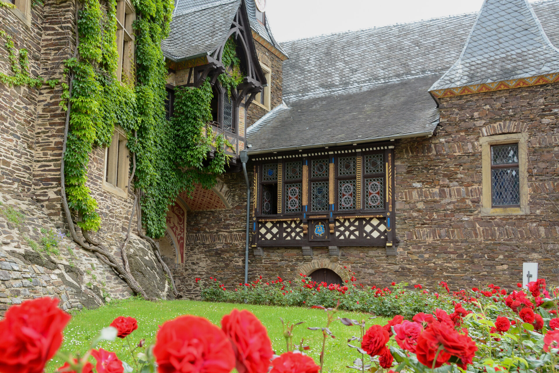 Detailaufnahme der Reichsburg Cochem mit Rosenbeet und Erker mit bleigefassten Fenstern