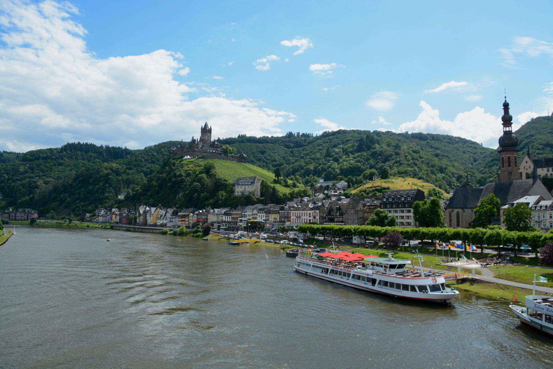 Blick auf die Mosel und das Rheinufer von Cochem mit Ausflugsschiffen