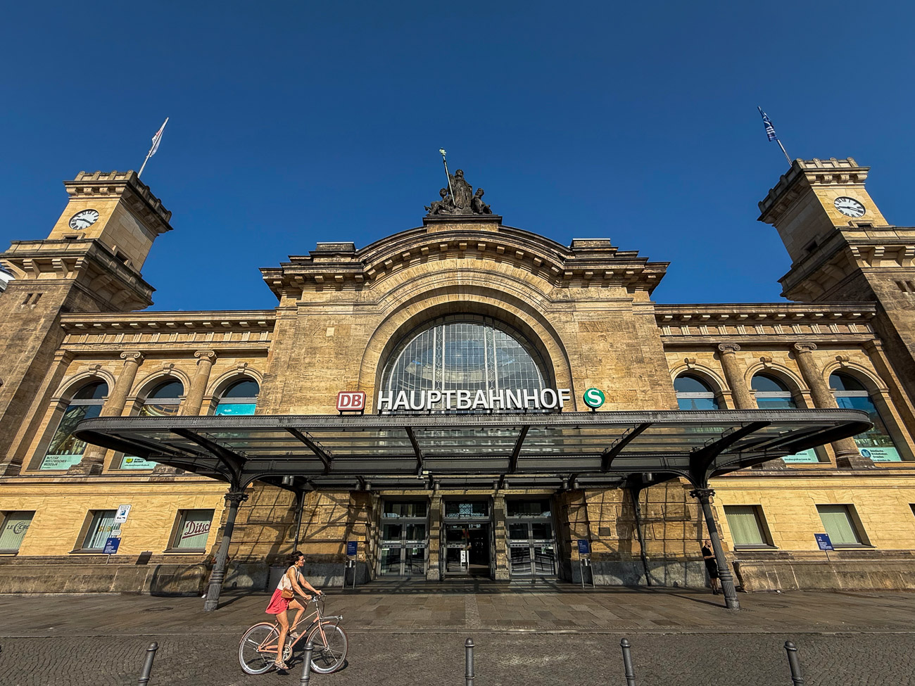 Aussenansicht des Dresdner Hauptbahnhofs mit Fahrradfahrerin im Sonnenschein