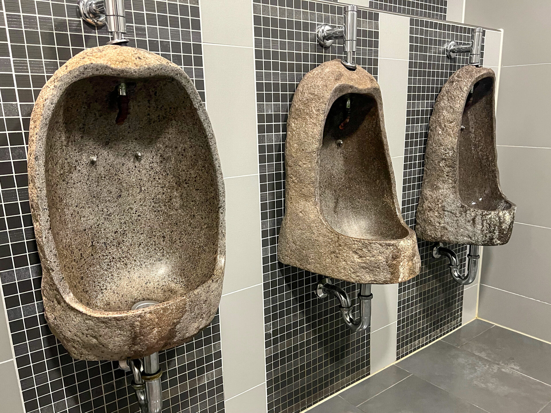 Auf Steinzeit getrimmte Pissoirs in einem Supermarkt in Schöningen, Niedersachsen