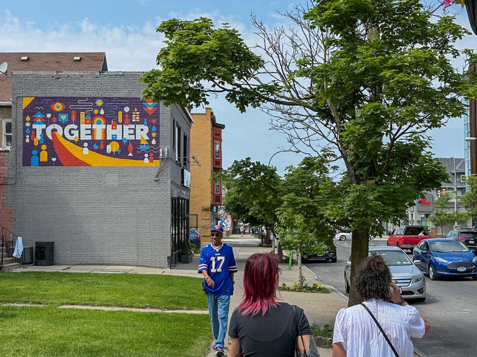 Fußgänger auf der Elmwood Avenue in Buffalo, New York, mit regenbogenfarbenem Wandgemälde